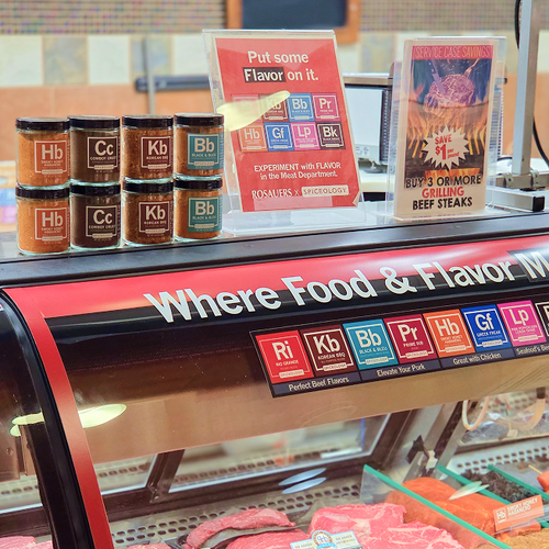Spiceology products on display in a retail store setting with branded signage and rows of spice jars on shelving