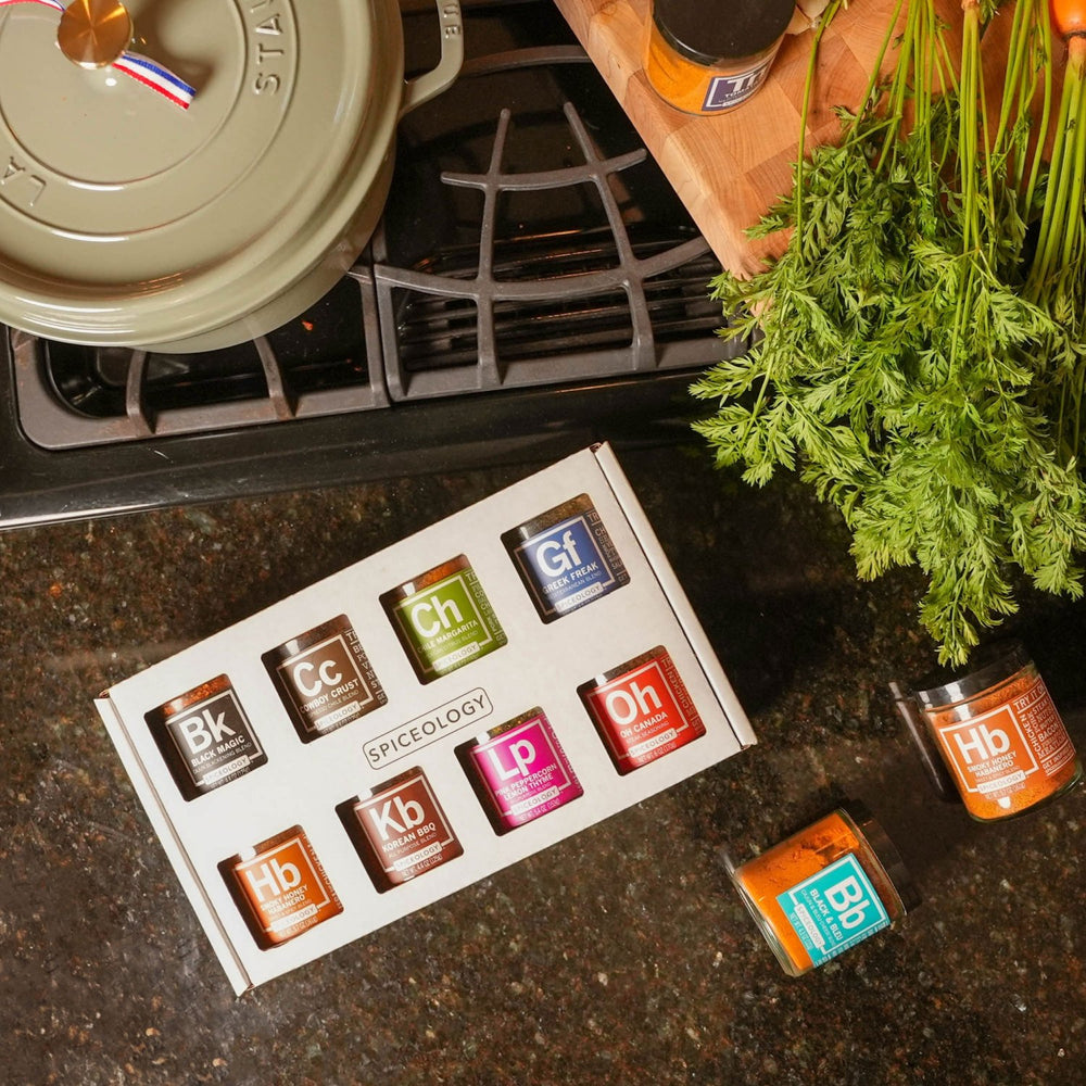 Spiceology 8-pack mini jar gift tray arranged on a counter with fresh herbs