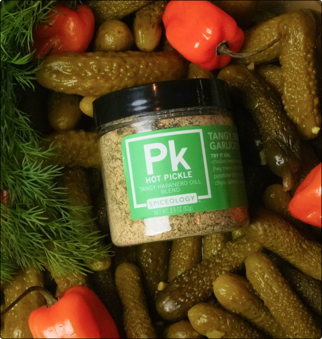 Jar of Spiceology Hot Pickle Tangy Habanero Dill Blend surrounded by pickles and peppers
