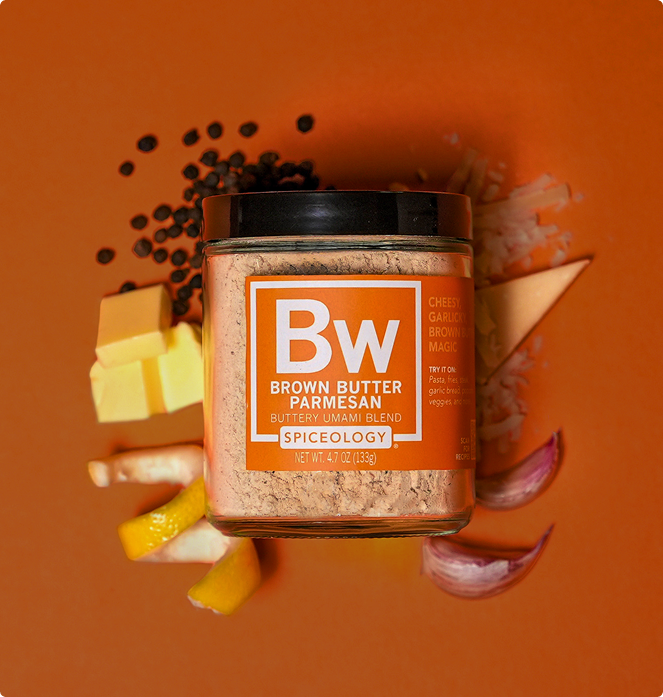 Spiceology Brown Butter Parmesan Seasoning surrounded by real brown butter, Parmesan cheese, lemon peel, onion, and black pepper on an orange background.