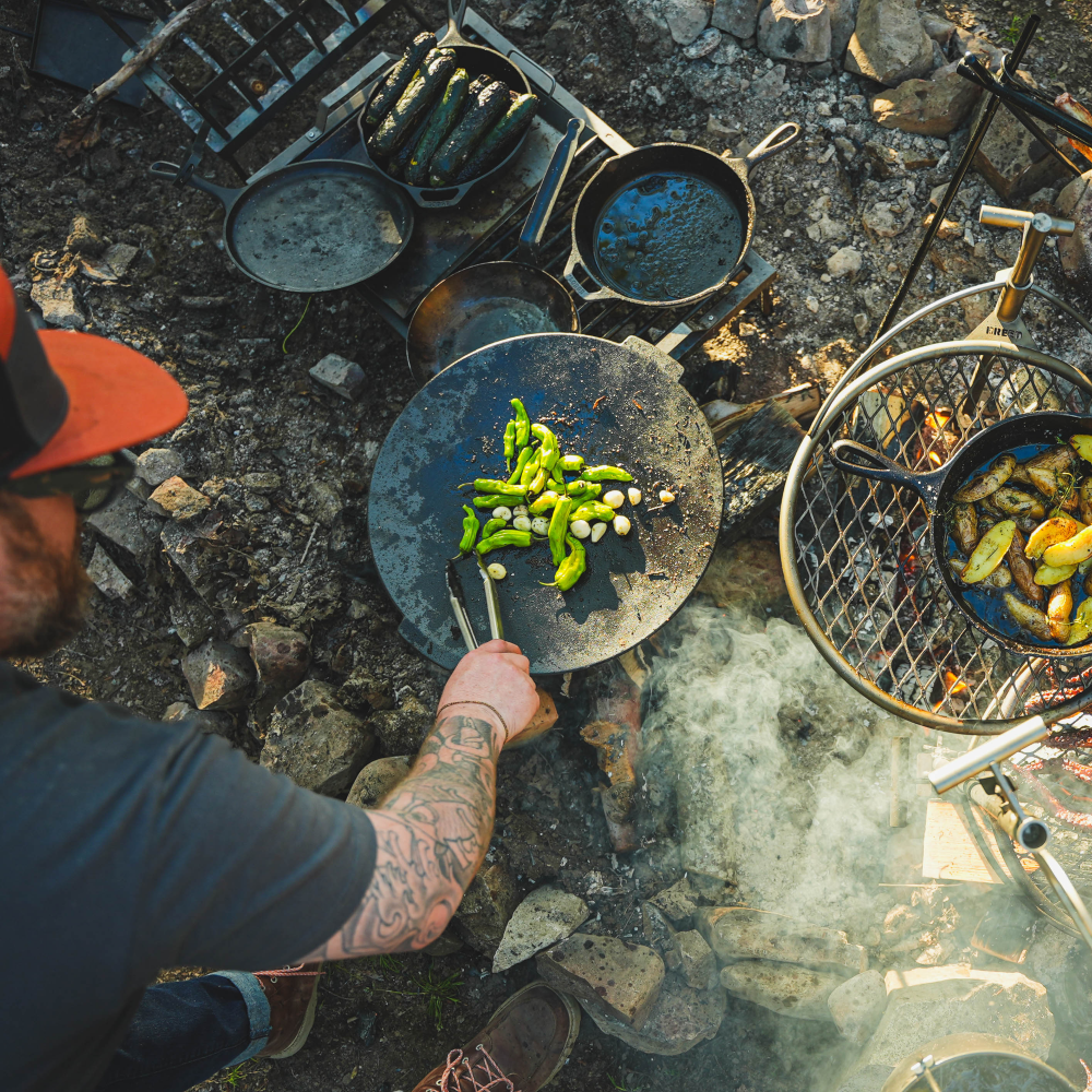 A hiker enjoying a hot meal from a camping stove while sitting at a scenic mountain overlook during sunset