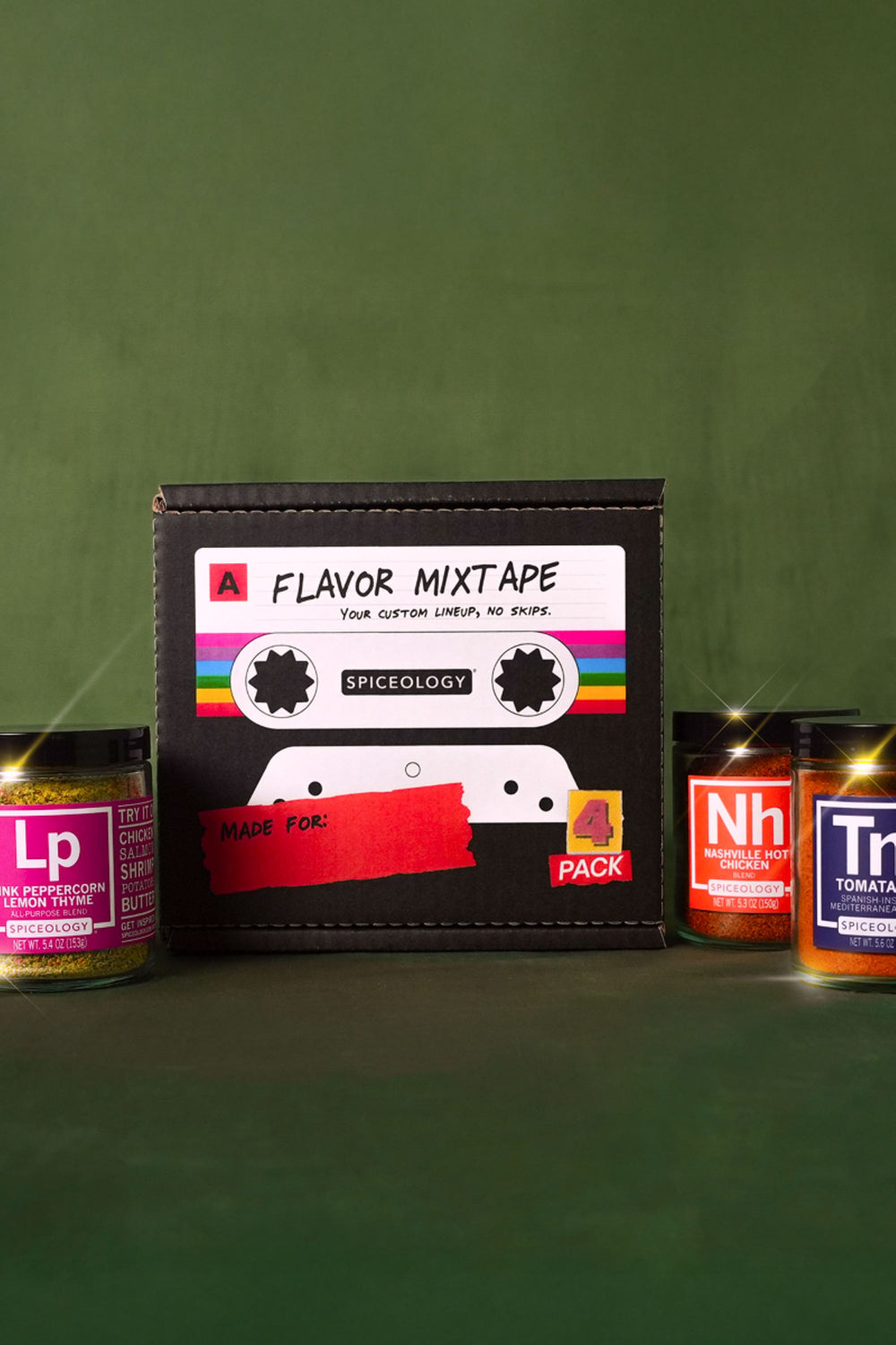 Spiceology Flavor Mixtape 4-pack cassette-tape gift box with Pink Peppercorn Lemon Thyme, Nashville Hot Chicken, and Tomatador spice blend jars on a moody green backdrop