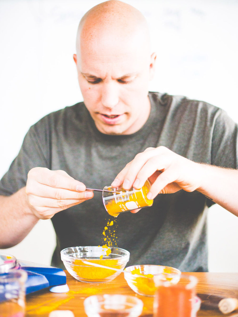 A man drizzling liquid into a jar at a workstation, likely during product development or flavor testing