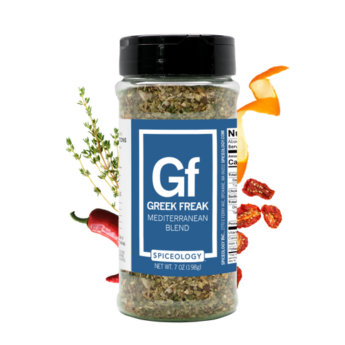 Spiceology Greek Freak blend large jar on black background with fresh herbs and spices arranged nearby