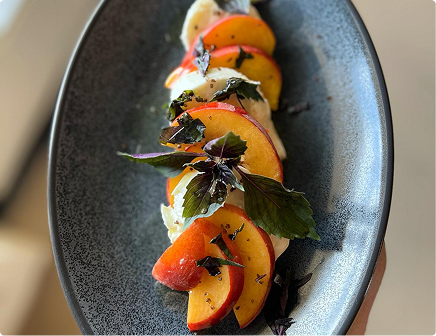Plated shrimp with citrus and orange garnish arranged on a dark ceramic plate