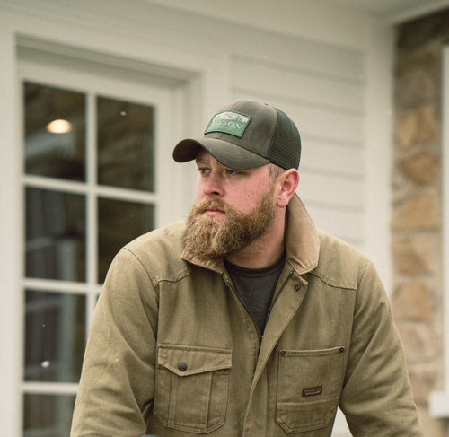 Portrait of a culinary collaborator wearing a baseball cap outdoors near a white building